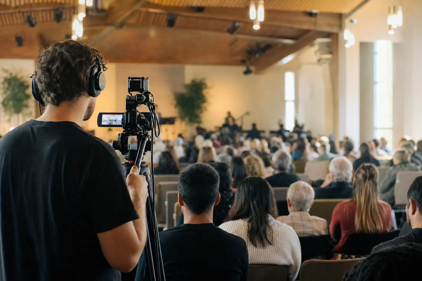 A camera operator films the Sunday service from the back of the room.