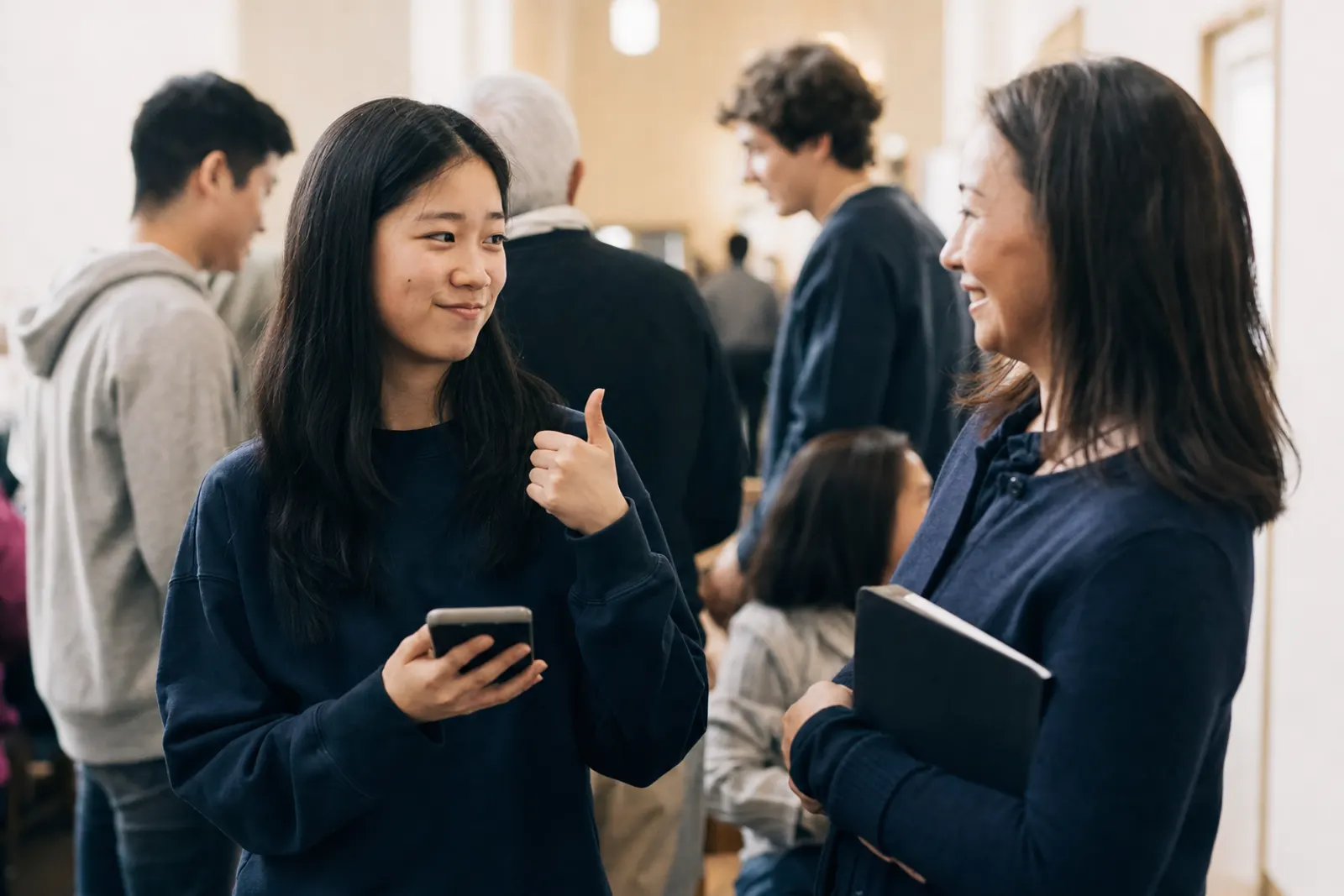 A teenage volunteer checks her phone and gives her team leader a thumbs-up.
