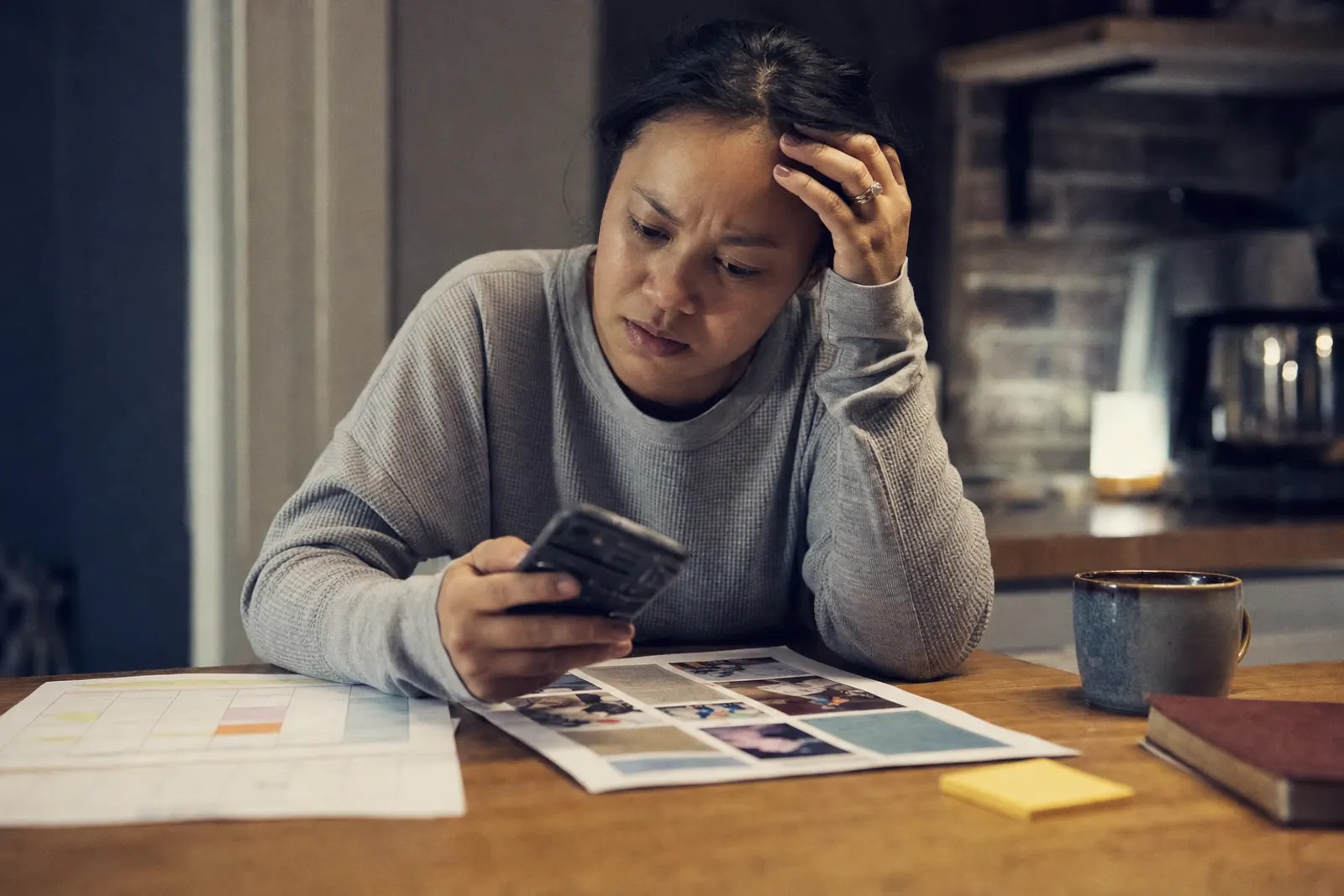 Hands holding a phone over a paper bulletin, a printed calendar and a sticky note.