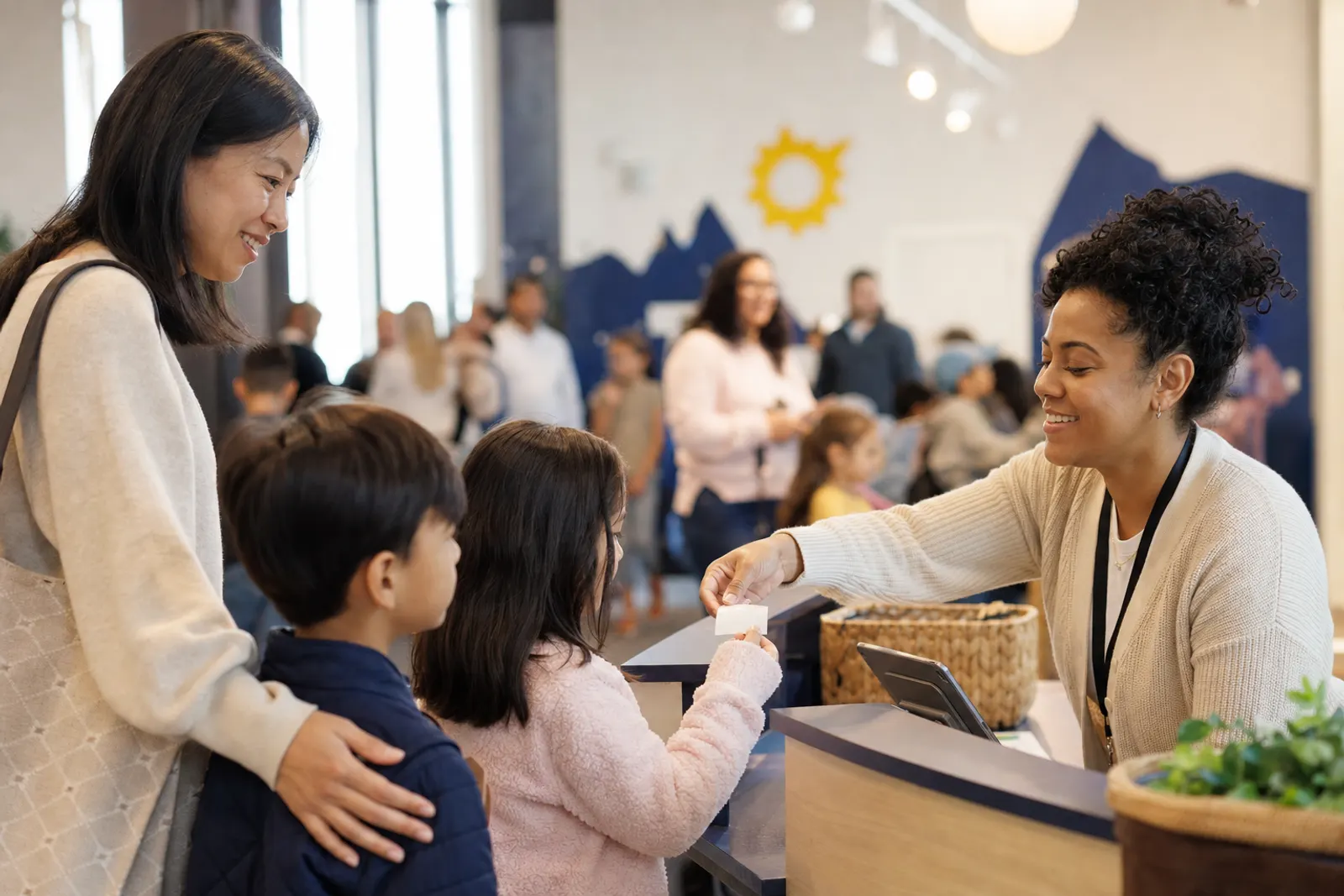 A parent checks in two children at the kids' check-in station.