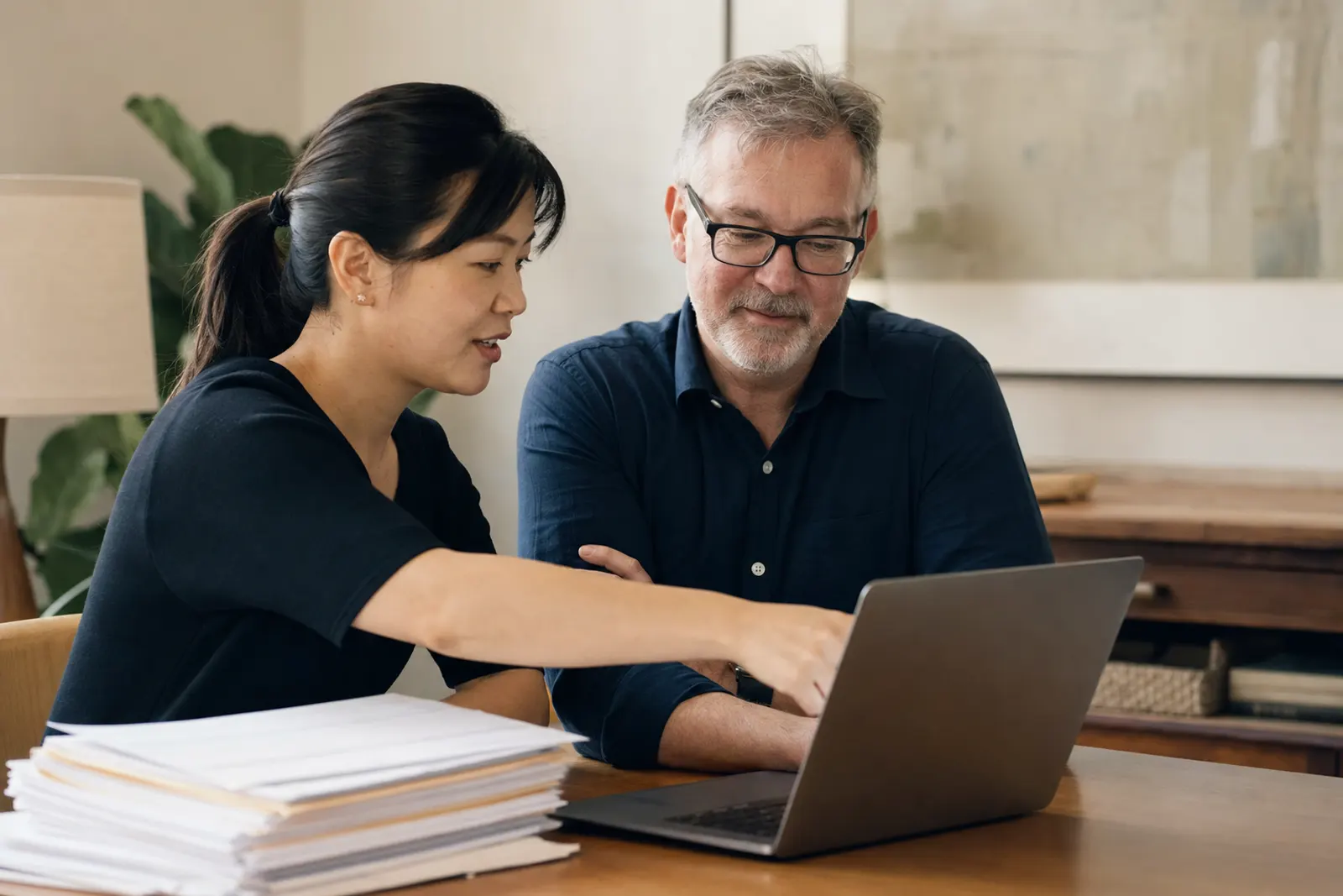 Two staff members review an import list on a laptop together.